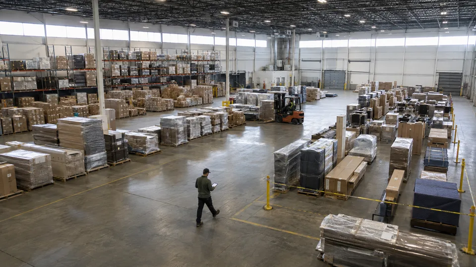 Plancher d’entrepôt avec stockage sur rayonnage d’un côté et fret filmé préparé pour la sortie de l’autre
